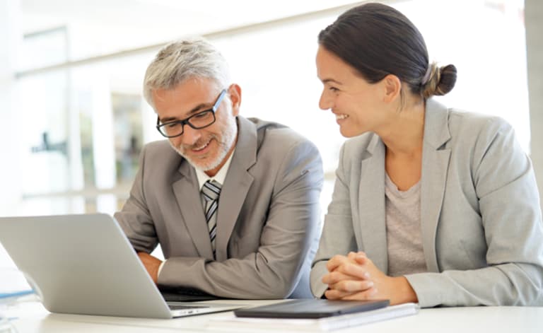 two people looking at laptop screen in office setting