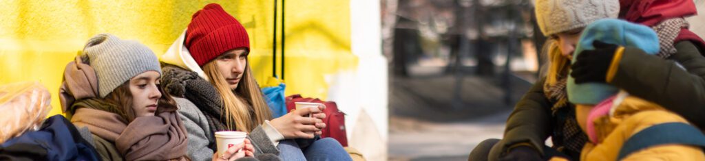 two women with coffee sitting on wall